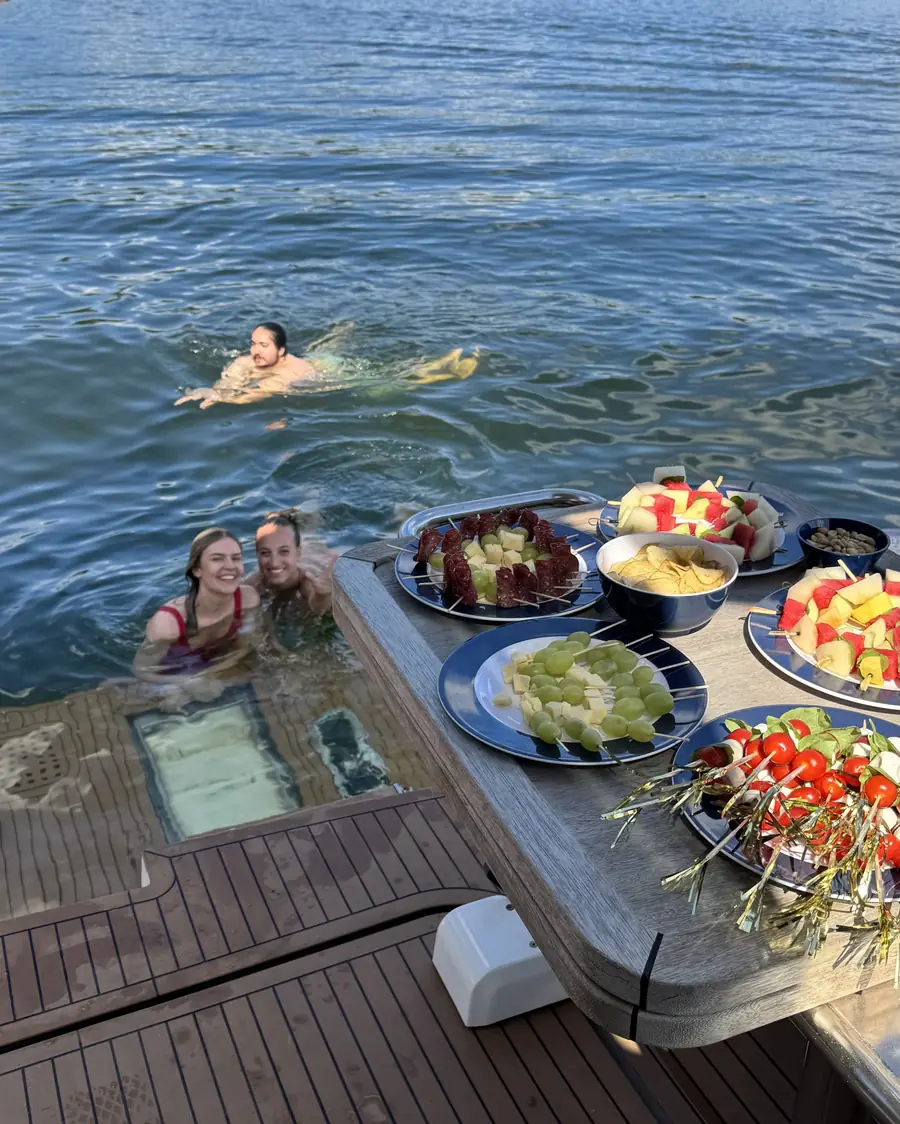 Gäster badar bredvid båten medan ett fruktfat väntar på däck