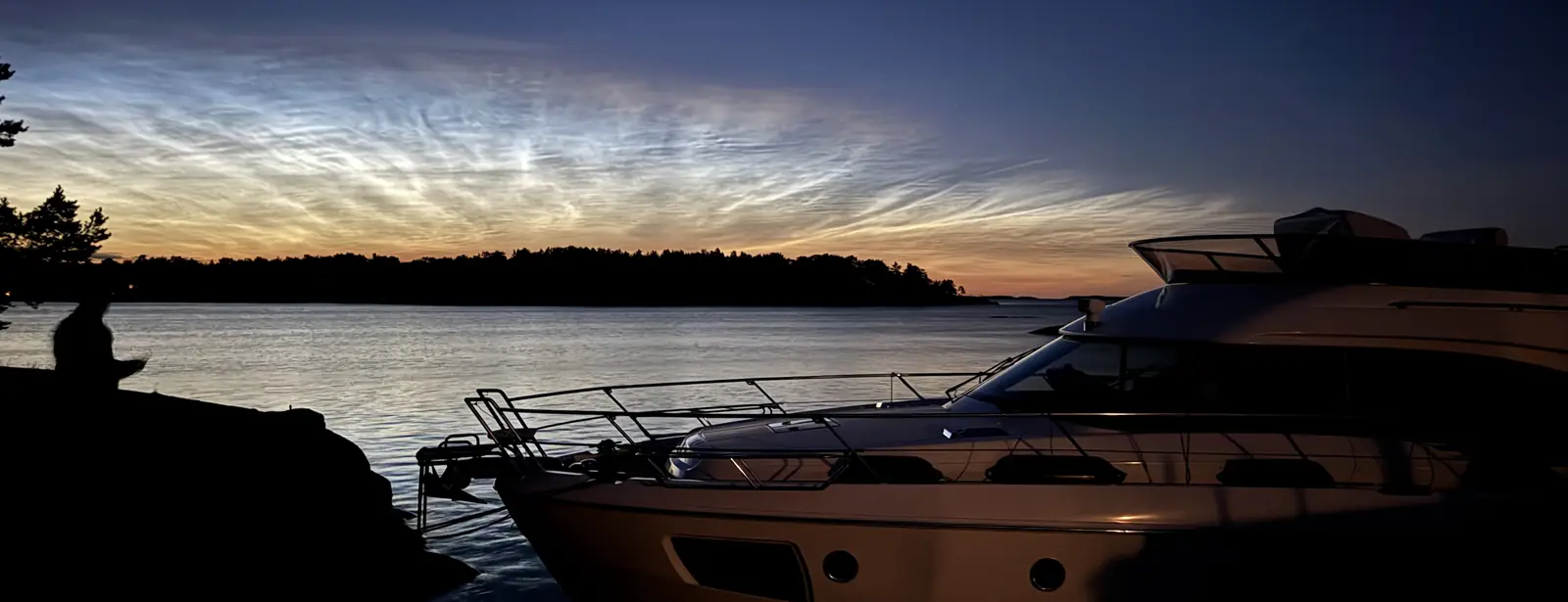 Båten i siluett mot en glödande solnedgång i skärgården