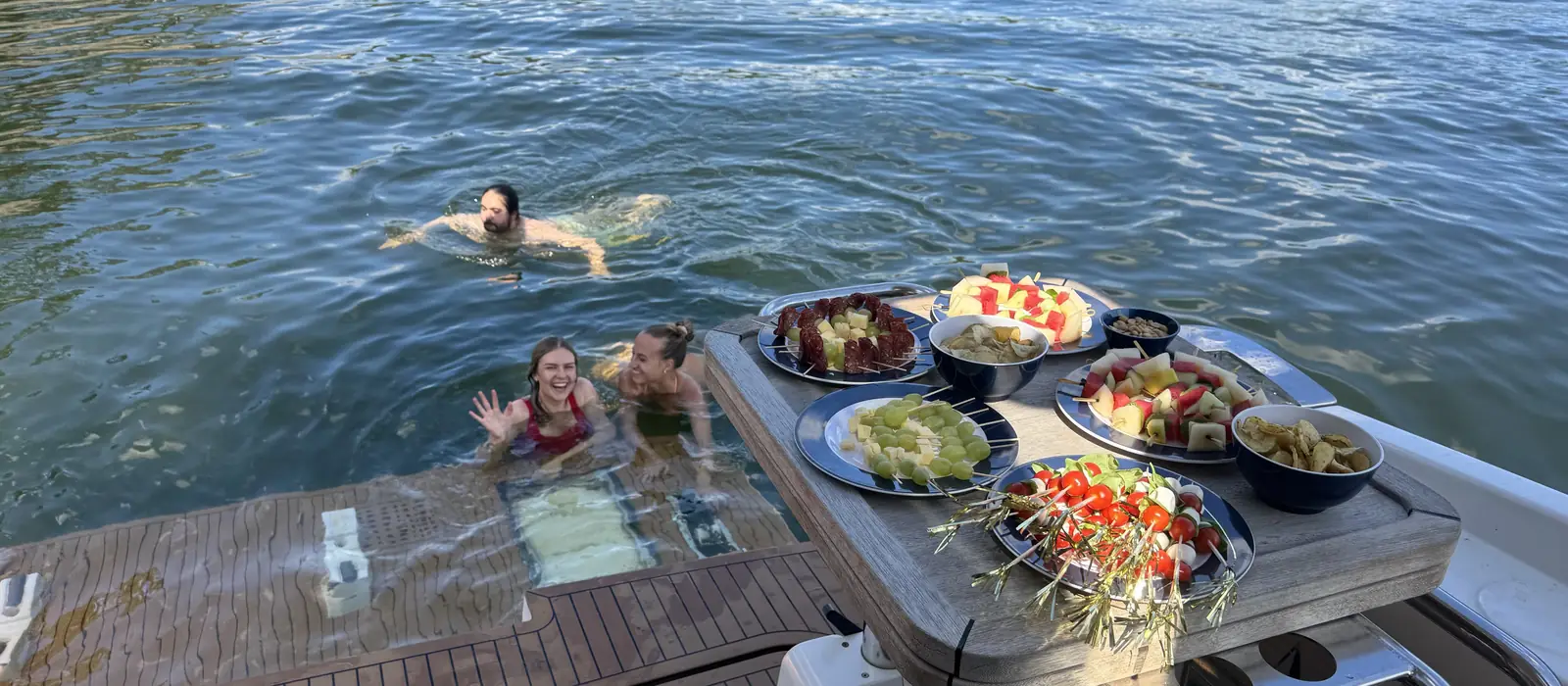 Gäster badar bredvid båten med frukt på däck